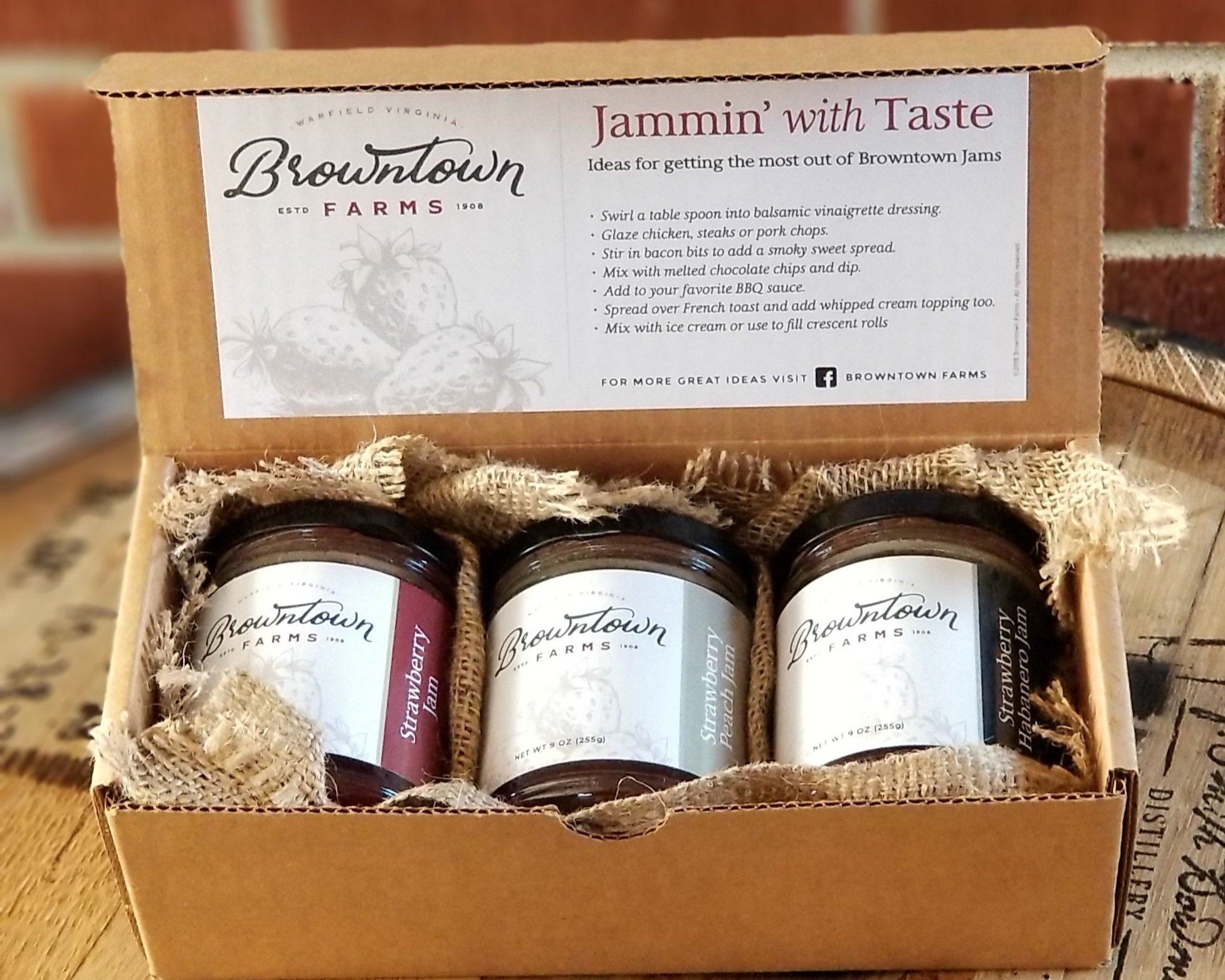 Browntown+Farms+-+Virginia+-+20191207_114929 Browntown Farms jam gift box featuring three jars of unique jams, including Strawberry and Strawberry Jalapeño, with a recipe card providing creative serving suggestions. The box is presented with rustic burlap and is set against a wooden background, emphasizing its artisanal quality.