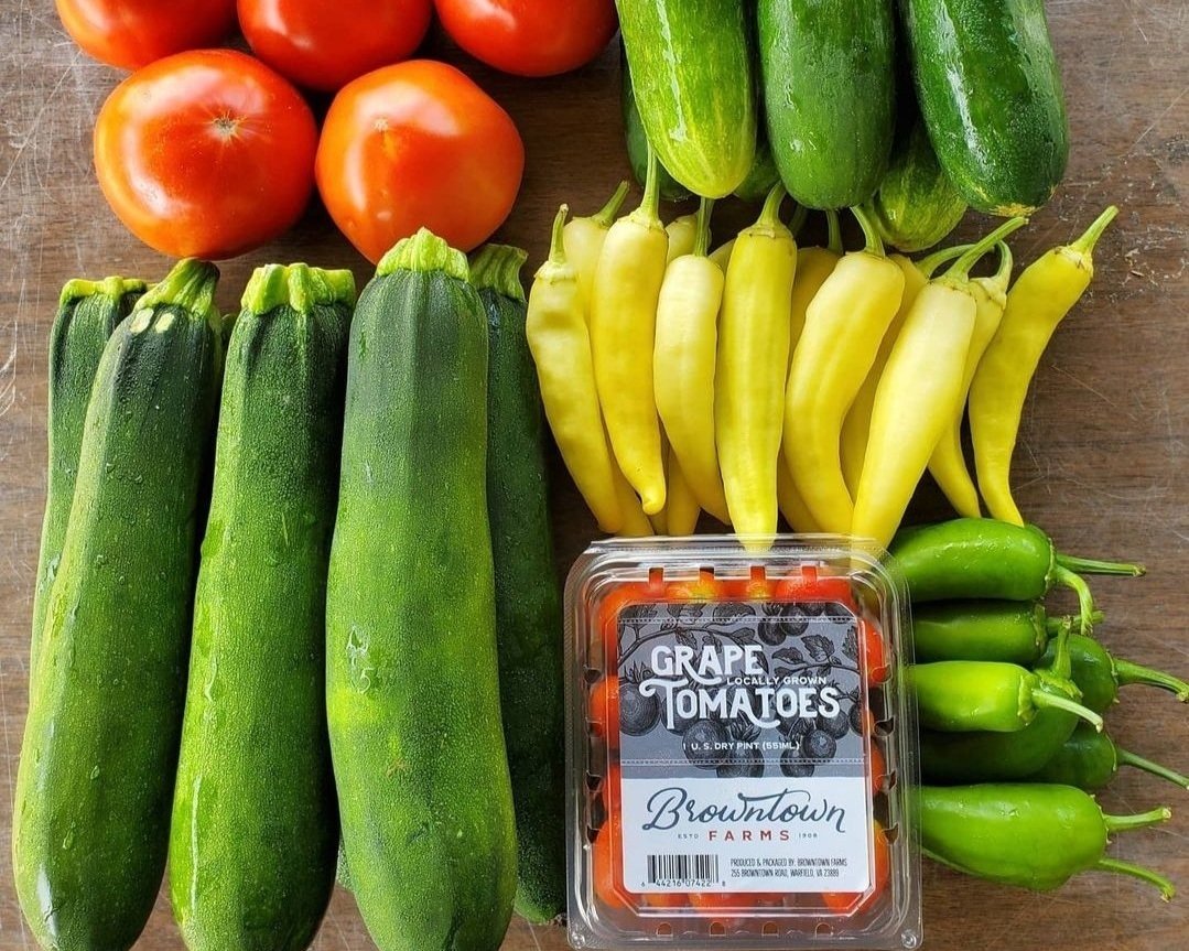 Browntown+Farms+-+Virginia+-+Screenshot_20220214-211611_Instagram Fresh produce display featuring ripe tomatoes, zucchini, yellow chili peppers, and green jalapeños, with a container of grape tomatoes from Browntown Farms. Ideal for healthy cooking and meal preparation.